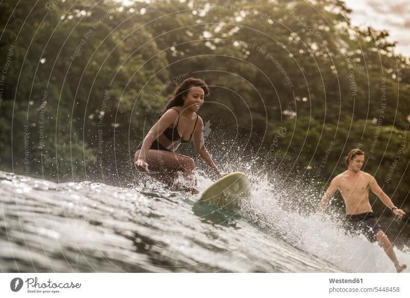 Indonesien, Java, glückliche Frau und Mann beim Surfen Welle Wellen Meer Meere Paar Pärchen Paare Partnerschaft Surfing Wellenreiten Wasser Gewässer Mensch