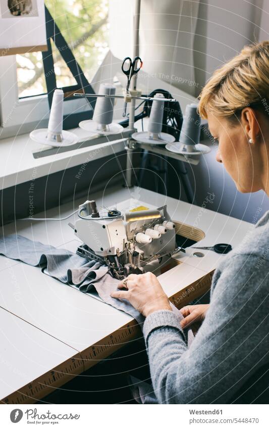 Frau mit Nähmaschine auf dem Tisch im Atelier weiblich Frauen arbeiten Arbeit Nähmaschinen Naehmaschinen Schneiderin Schneiderinnen nähen naehen Erwachsener