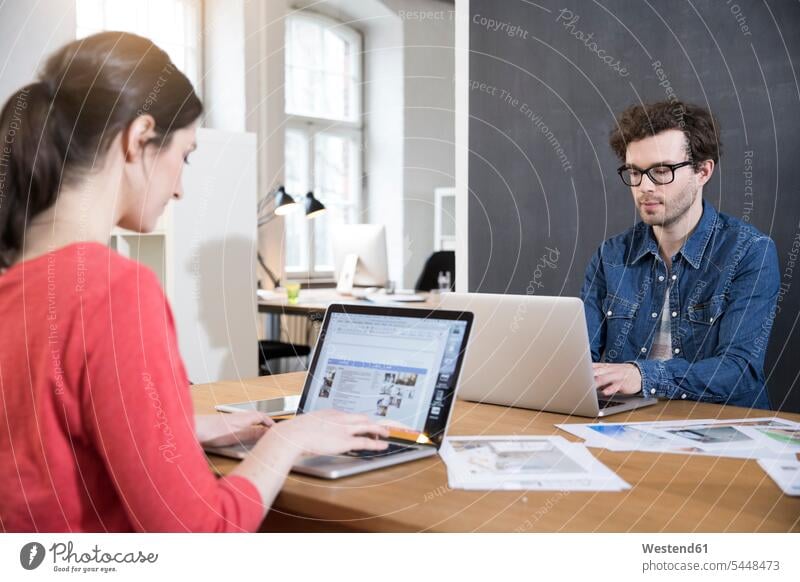 Mann und Frau benutzen Laptops auf Tischen im Büro Office Büros Arbeitsplatz Arbeitsstätte Arbeitstelle Notebook Notebooks Kollegen Arbeitskollegen arbeiten