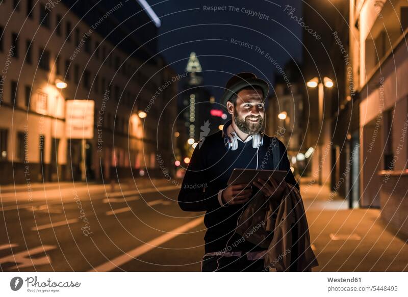 Stilvoller junger Mann mit Tablette auf nächtlicher Stadtstraße lächeln Nacht nachts Männer männlich Tablet Computer Tablet-PC Tablet PC iPad Tablet-Computer