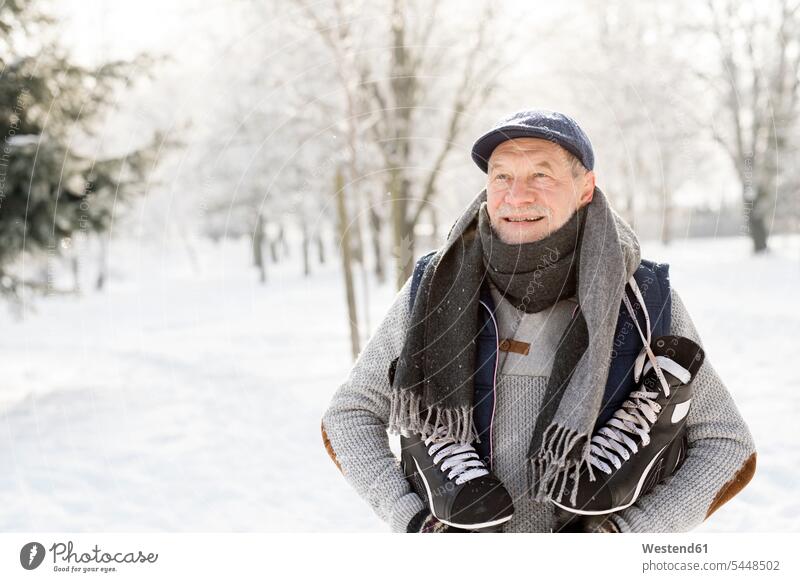 Lächelnder älterer Mann mit Schlittschuhen im Winterwald Schlittschuhläufer Schlittschuhlaeufer Senior ältere Männer Senioren Wald Forst Wälder Spaß Spass Späße