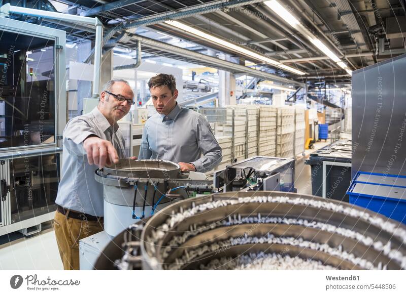 Zwei Männer in der Fabrikhalle untersuchen das Ergebnis einer Maschine sprechen reden Fabriken Kollegen Arbeitskollegen Mann männlich Erwachsener erwachsen