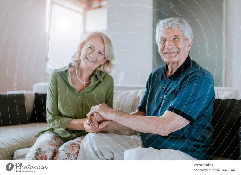 Porträt eines lächelnden älteren Paares zu Hause Pärchen Partnerschaft Sofa Couches Liege Sofas Senior ältere Männer älterer Mann Senioren Mensch Menschen Leute