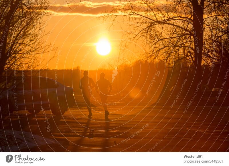 Silhouette von zwei Joggern im Winter bei Sonnenuntergang trainieren Joggen Jogging laufen rennen Fitness fit Gesundheit gesund Sport winterlich Winterzeit
