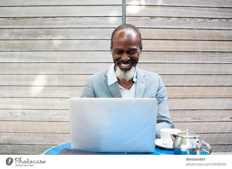 Porträt eines lachenden bärtigen Mannes mit Laptop Geschäftsmann Businessmann Businessmänner Geschäftsmänner Notebook Laptops Notebooks Geschäftsleute