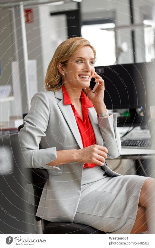 Geschäftsfrau am Schreibtisch im Büro am Mobiltelefon lächeln Office Büros telefonieren anrufen Anruf telephonieren Handy Handies Handys Mobiltelefone