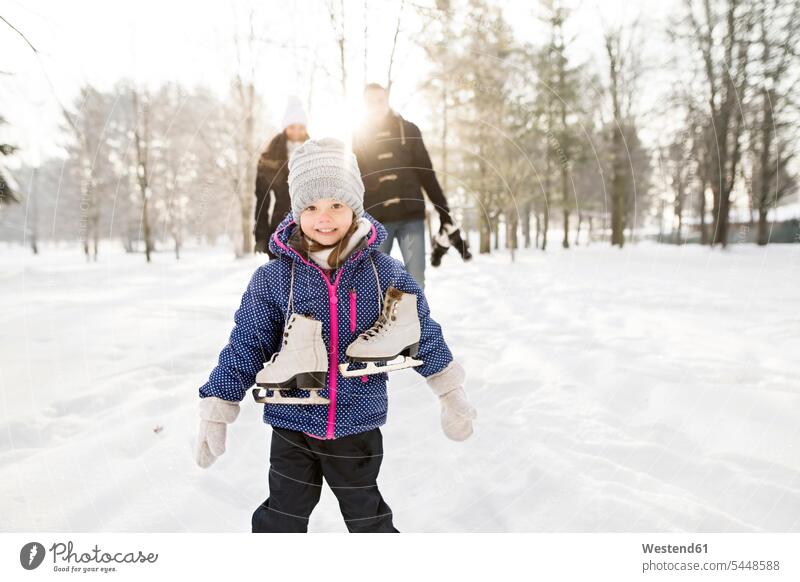 Kleines Mädchen geht mit ihren Eltern Schlittschuh laufen Sonne Schlittschuhlaufen Eislaufen eislaufen schlittschuhlaufen weiblich frech Frechheit Winter