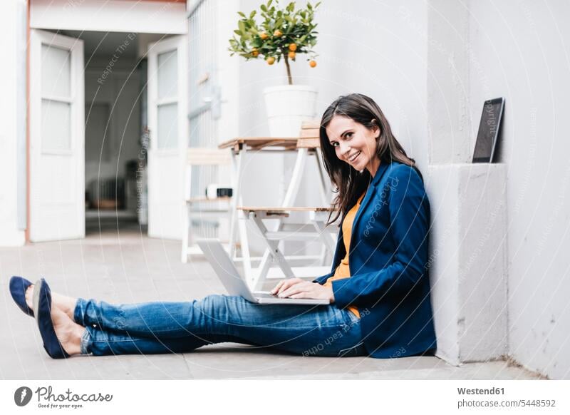 Lächelnde Geschäftsfrau mit Laptop auf dem Boden Notebook Laptops Notebooks attraktiv schoen gut aussehend schön Attraktivität gutaussehend hübsch Frau weiblich