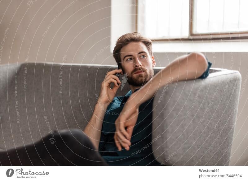 Porträt eines jungen Mannes am Telefon, der auf der Couch sitzt Männer männlich telefonieren anrufen Anruf telephonieren Erwachsener erwachsen Mensch Menschen