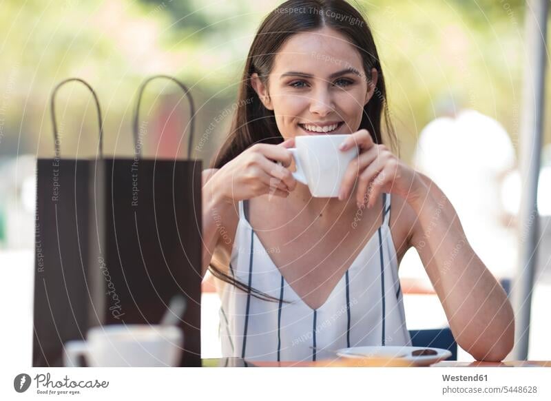 Lächelnde Frau mit Einkaufstasche genießt Kaffee im Café glücklich Glück glücklich sein glücklichsein lächeln einkaufen Einkaufen shoppen shopping Shopping