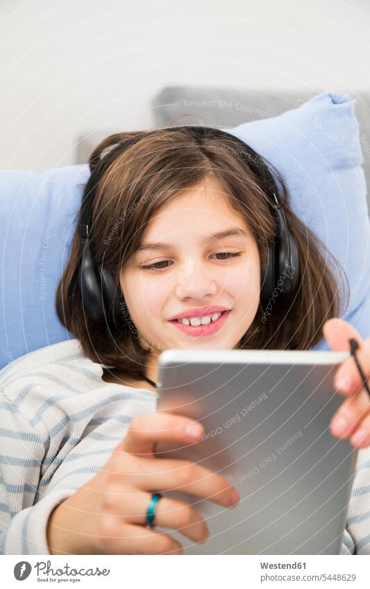 Porträt eines lächelnden Mädchens mit Tablette und Kopfhörer zu Hause benutzen Portrait Zuhause Kind Mensch Computer Neugier Freude Entspannung Technologie