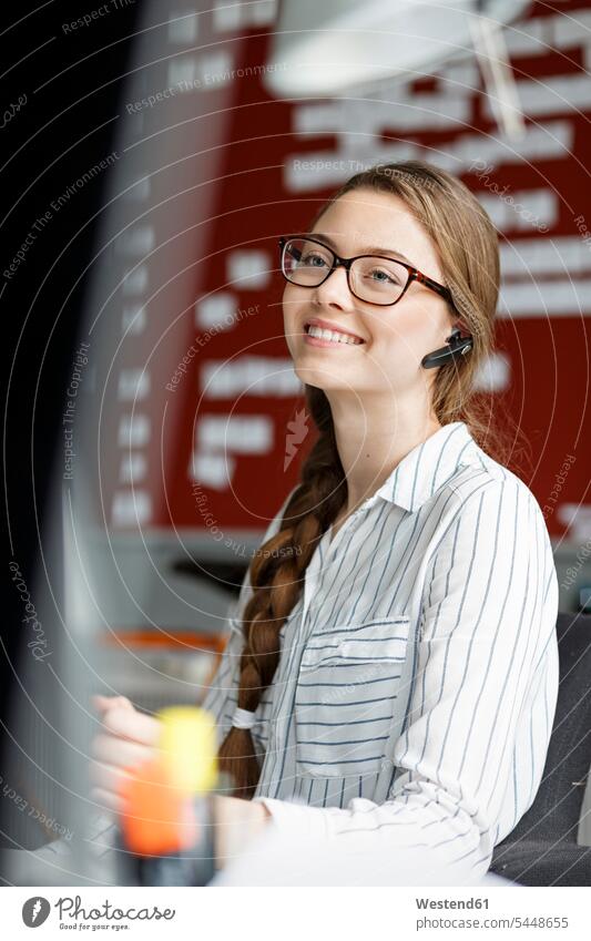 Lächelnde junge Frau im Büro mit Headset Office Büros Headsets lächeln Arbeitsplatz Arbeitsstätte Arbeitstelle Kommunikation Telekommunikation Business