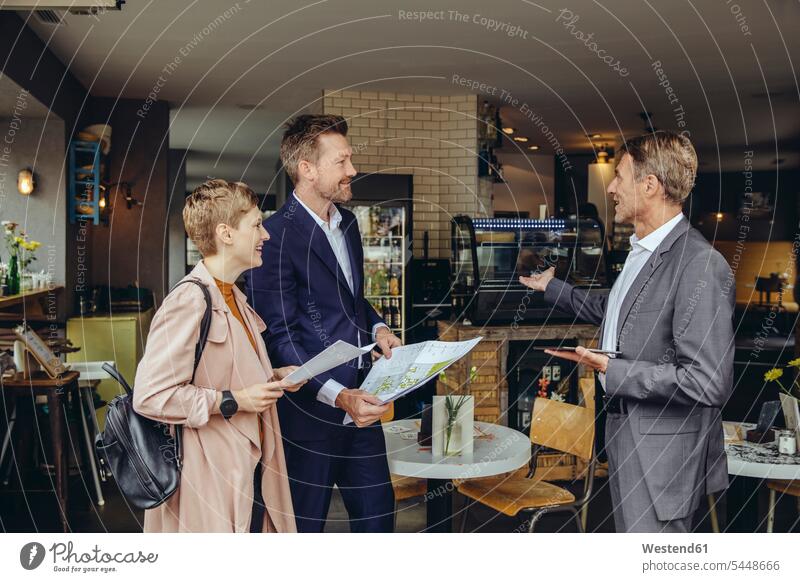 Frau und zwei Geschäftsleute besprechen Pläne in einem Cafe Kaffeehaus Bistro Cafes Café Cafés Kaffeehäuser lächeln Planung planen reden Geschäftspartner