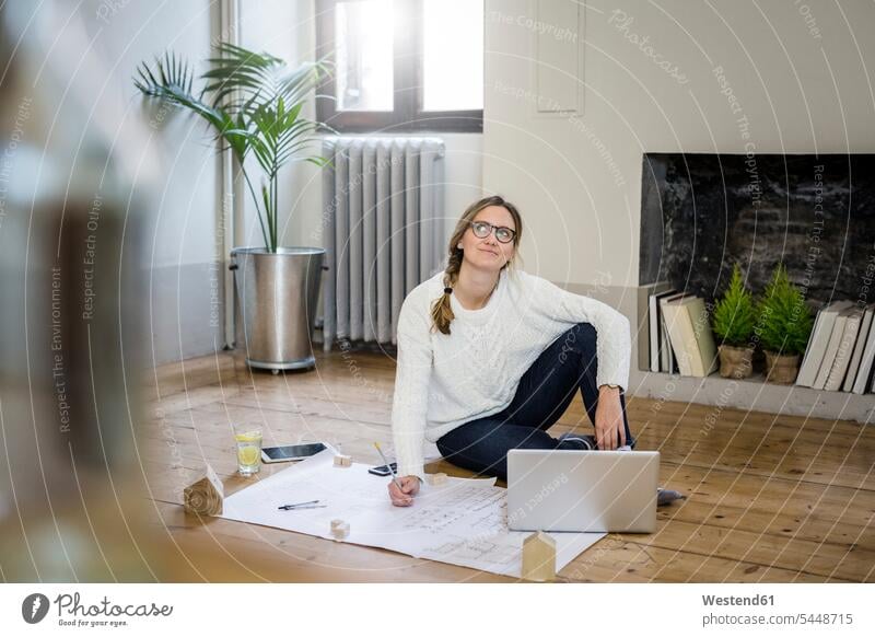 Auf dem Boden sitzende Frau mit Blaupause und Laptop Bauplan Architekturplan Konstruktionsplan Konstruktionszeichnung Bauzeichnung Notebook Laptops Notebooks
