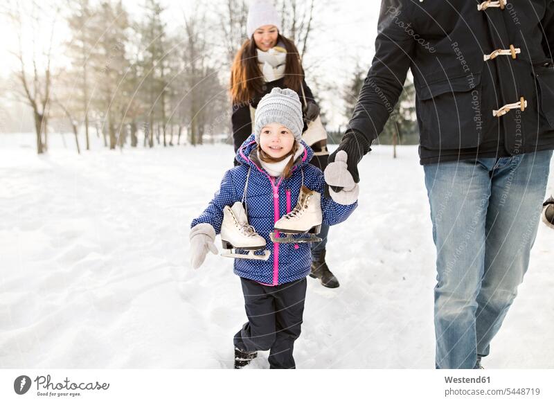 Kleines Mädchen geht mit ihren Eltern Schlittschuh laufen Schlittschuhlaufen Eislaufen weiblich Winter winterlich Winterzeit lächeln eislaufen