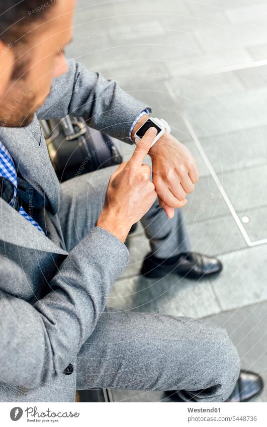 Nahaufnahme eines Geschäftsmannes, der seine Smartwatch in der Stadt benutzt sitzen sitzend sitzt Armbanduhr Armbanduhren Businessmann Businessmänner