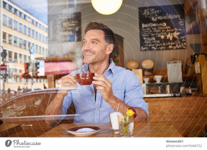 Porträt eines zögernden Mannes mit einer Tasse Kaffee in einem Kaffeehaus Cafe Bistro Cafes Kaffeehäuser lachen Fensterscheibe Fensterscheiben Kaffeetasse