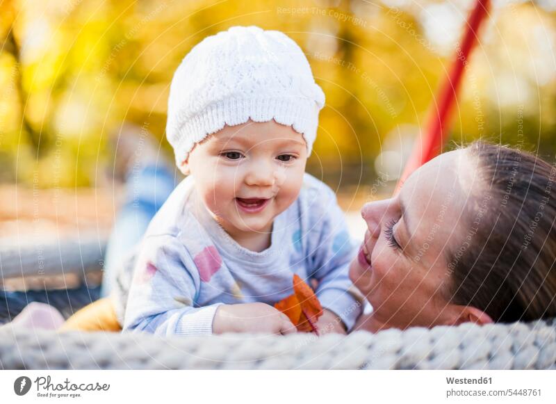 Porträt eines glücklichen Mädchens, das sich im Herbst mit seiner Mutter auf einer Schaukel entspannt Spielplatz Spielplätze Spielfeld Spielplaetze Mami Mutti