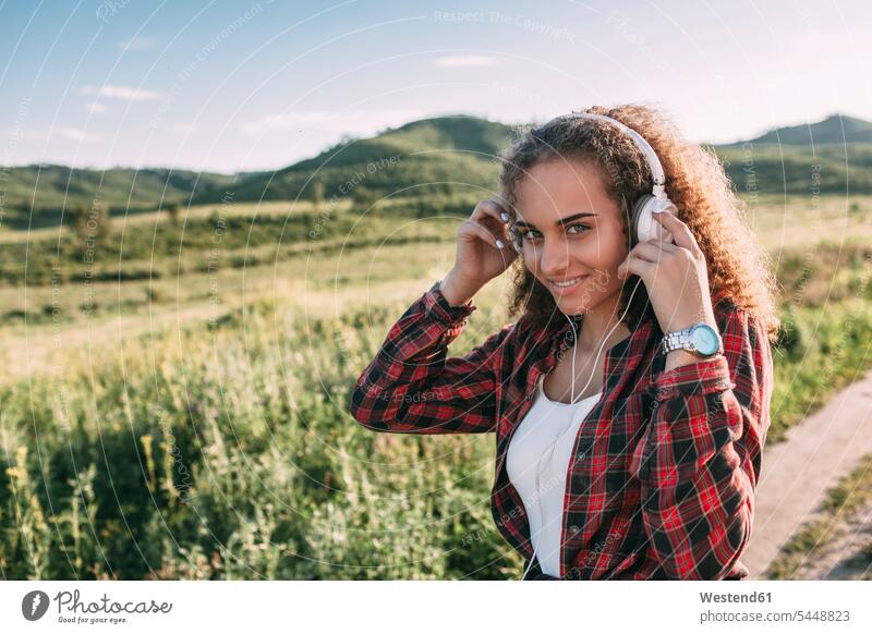 Teenager-Mädchen beim Musikhören mit Kopfhörern in der Natur Teenagerin junges Mädchen Teenagerinnen weiblich junge Frau Portrait Porträts Portraits Kopfhoerer