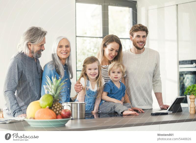 Glückliche Familie mit Großeltern und Kindern, die in der Küche stehen Gemeinsam Zusammen Miteinander Familientreffen Küchen glücklich glücklich sein