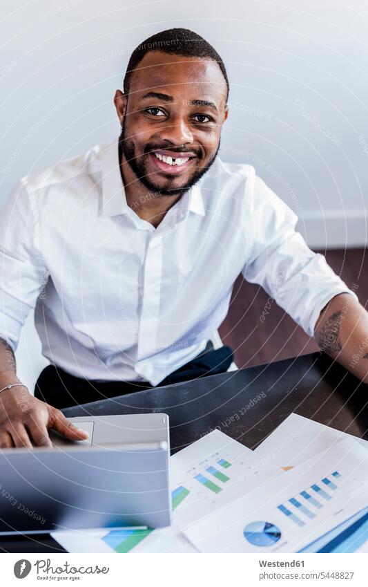 Porträt eines lächelnden Mannes, der Daten analysiert und einen Laptop am Schreibtisch im Heimbüro benutzt Männer männlich Geschäftsmann Businessmann