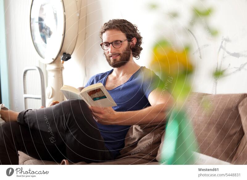 Porträt eines lächelnden jungen Mannes beim Lesen eines Buches in einem Café Bücher Männer männlich lesen Lektüre Erwachsener erwachsen Mensch Menschen Leute