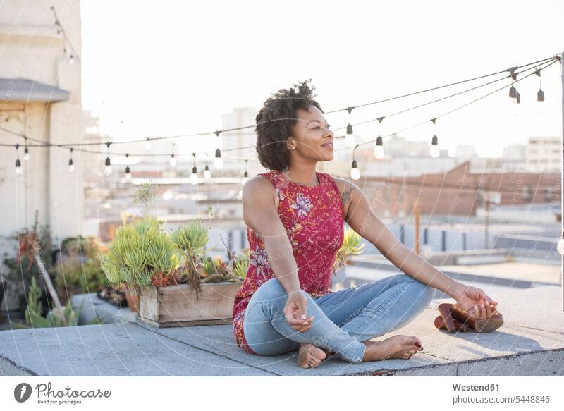 Junge Frau sitzt auf der Dachterrasse und genießt die Sonne Schneidersitz Entspannung relaxen entspannen nachdenken überlegen sitzen sitzend Dachterrassen