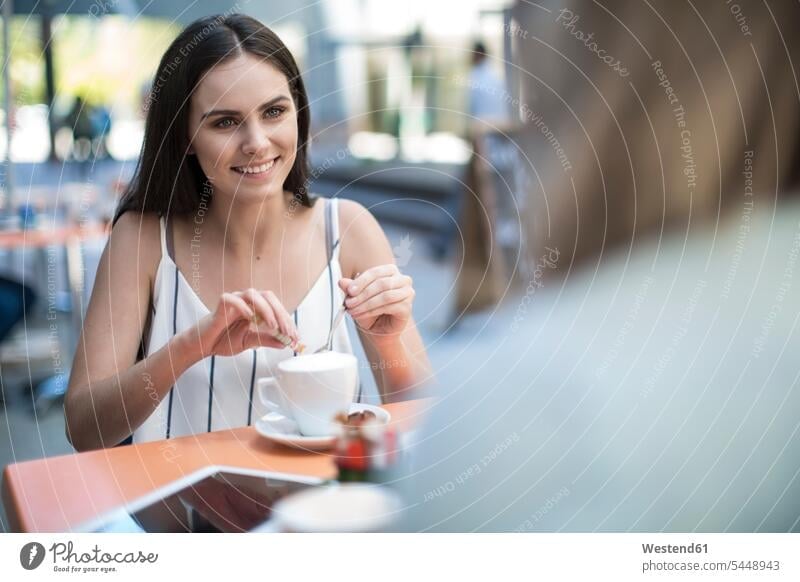 Lächelnde Frau schaut Freundin in einem Café im Freien an Cafe Kaffeehaus Bistro Cafes Cafés Kaffeehäuser Freundinnen glücklich Glück glücklich sein