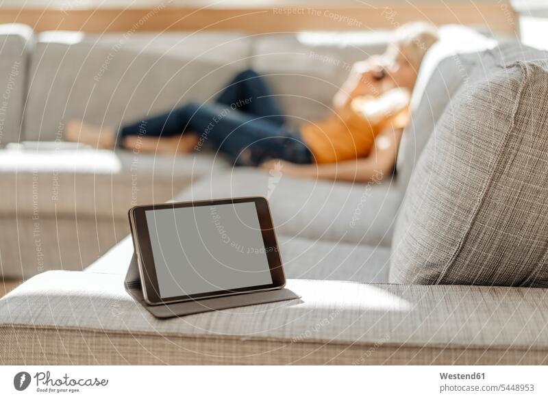 Tablett auf Couch mit entspannter Frau im Hintergrund Sofa Couches Liege Sofas weiblich Frauen entspanntheit relaxt Wohnzimmer Wohnraum Wohnung Wohnen Wohnräume
