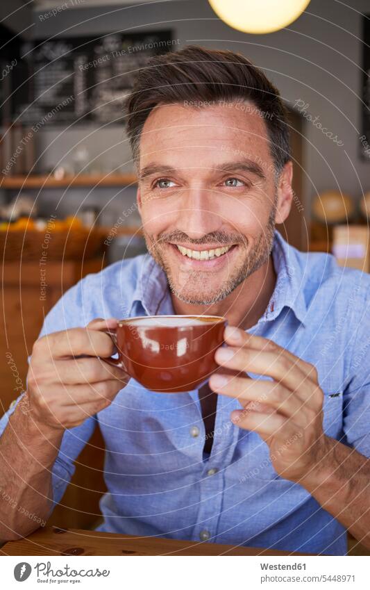 Porträt eines lachenden Mannes mit einer Tasse Kaffee in einem Kaffeehaus Kaffeetasse Kaffeetassen Portrait Porträts Portraits Männer männlich Cafe Bistro Cafes