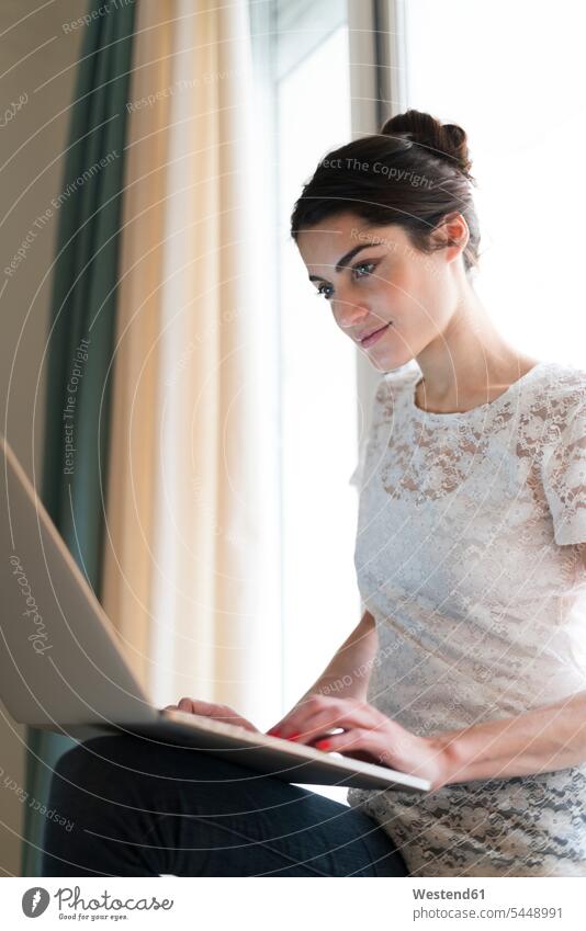 Porträt einer Frau, die mit einem Laptop auf dem Fensterbrett sitzt Portrait Porträts Portraits weiblich Frauen Notebook Laptops Notebooks Erwachsener erwachsen