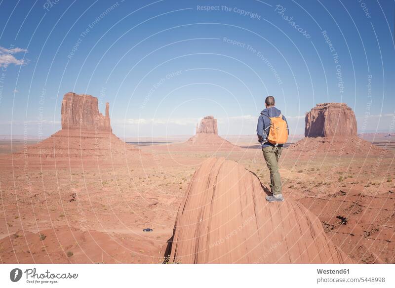 USA, Utah, Rückenansicht eines Mannes mit Rucksack beim Blick auf das Monument Valley Tourist Touristen Männer männlich Tourismus Erwachsener erwachsen Mensch