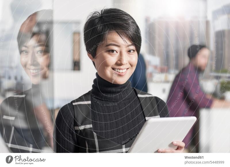 Porträt einer lächelnden Frau, die im Amt eine Tafel hält Büro Office Büros Portrait Porträts Portraits weiblich Frauen Tablet Tablet Computer Tablet-PC