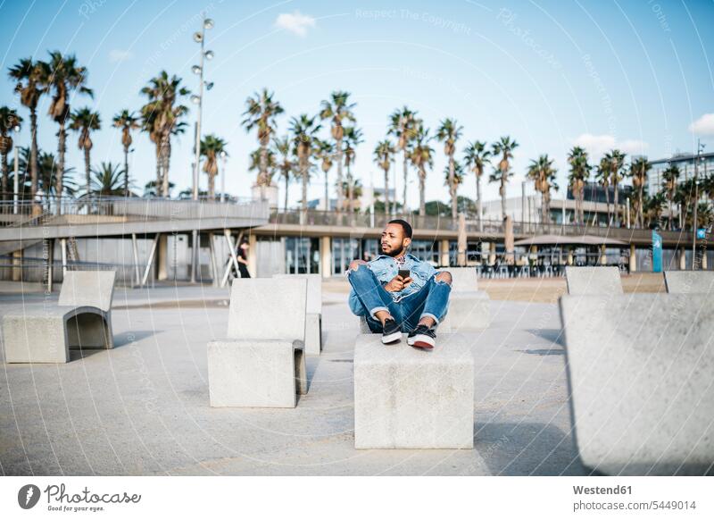 Spanien, Barcelona, junger Mann entspannt sich an der Strandpromenade sitzen sitzend sitzt Männer männlich Erwachsener erwachsen Mensch Menschen Leute People