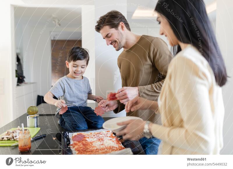 Familie bereitet gemeinsam Pizza in der Küche zu Sohn Söhne Familien lächeln kochen Pizzen Vater Papas Väter Vati Vatis Papis Küchen Kind Kinder Mensch Menschen