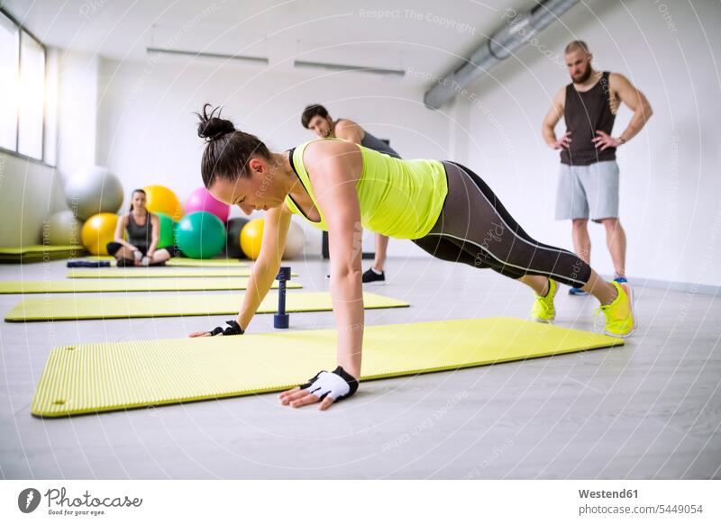 Frau trainiert im Fitnessstudio unter Beobachtung von Trainingspartnern trainieren Liegestützen Push-Up Pushups Push-Ups Fitnessclubs Fitnessstudios Turnhalle