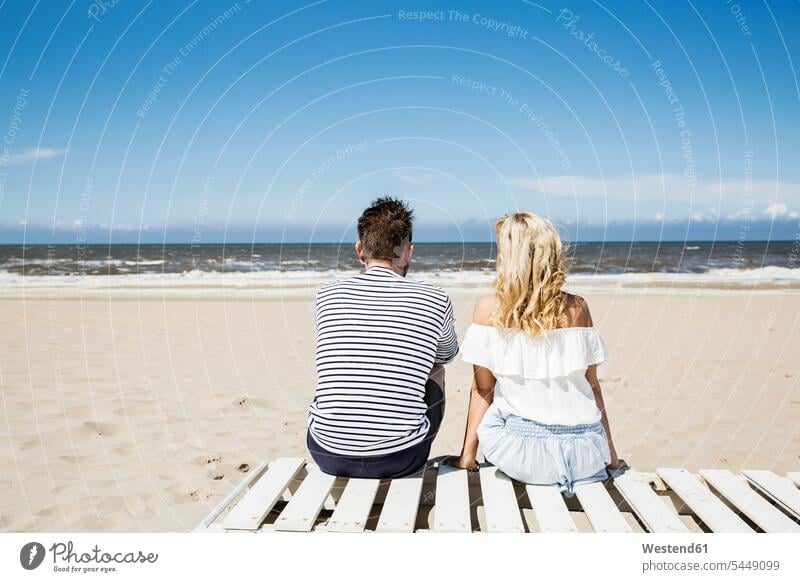 Ehepaar sitzt auf der Strandpromenade Beach Straende Strände Beaches sitzen sitzend entspannt entspanntheit relaxt Paar Pärchen Paare Partnerschaft Entspannung
