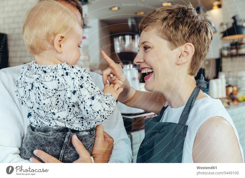 Kellnerin spielt mit dem Baby eines Kunden im Cafe Spaß Spass Späße spassig Spässe spaßig Portrait Porträts Portraits Kaffeehaus Bistro Cafes Café Cafés