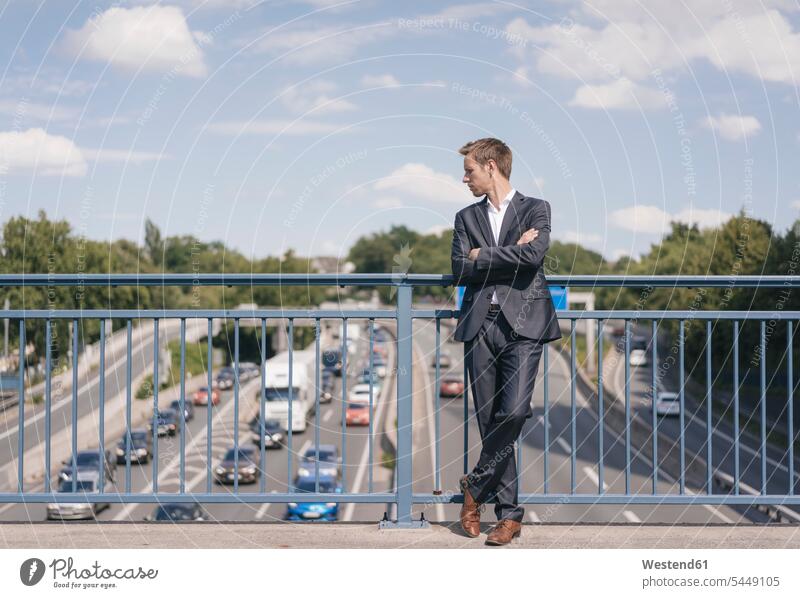 Geschäftsmann steht auf einer Brücke über eine Autobahn Verkehr Businessmann Businessmänner Geschäftsmänner Bruecken Brücken Wagen PKWs Automobil Autos stehen