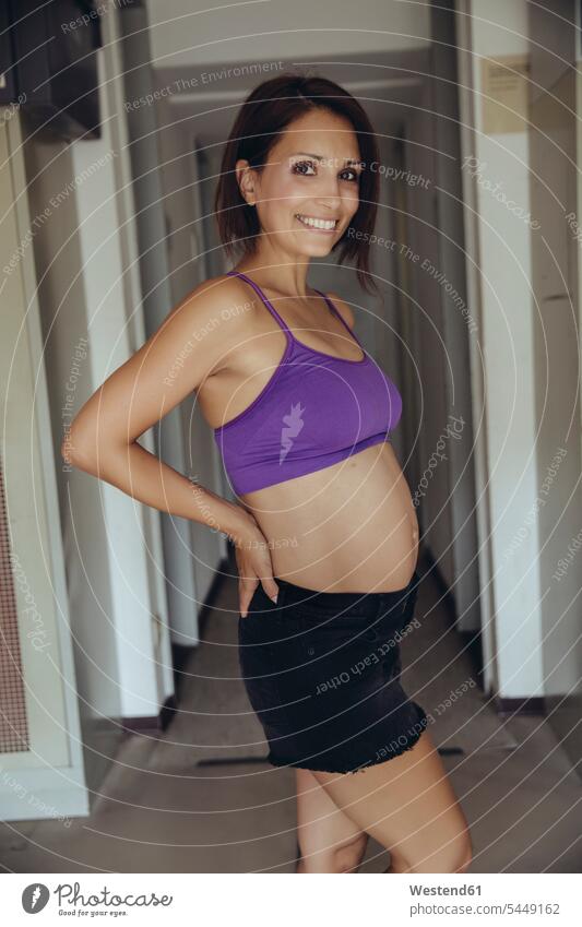 Porträt einer lächelnden, sportlichen, schwangeren Frau stehend Portrait Porträts Portraits Schwangere schwangere Frau weiblich Frauen Bauch Bäuche Umkleide