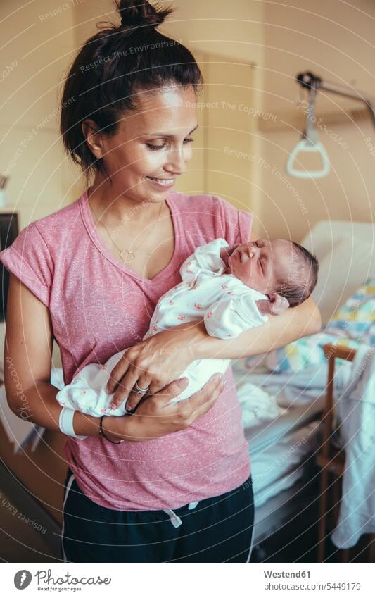 Glückliche Mutter hält ihr Neugeborenes im Krankenhaus Mami Mutti Mütter Mama Baby Babies Babys Säuglinge Kind Kinder Eltern Familie Familien Mensch Menschen