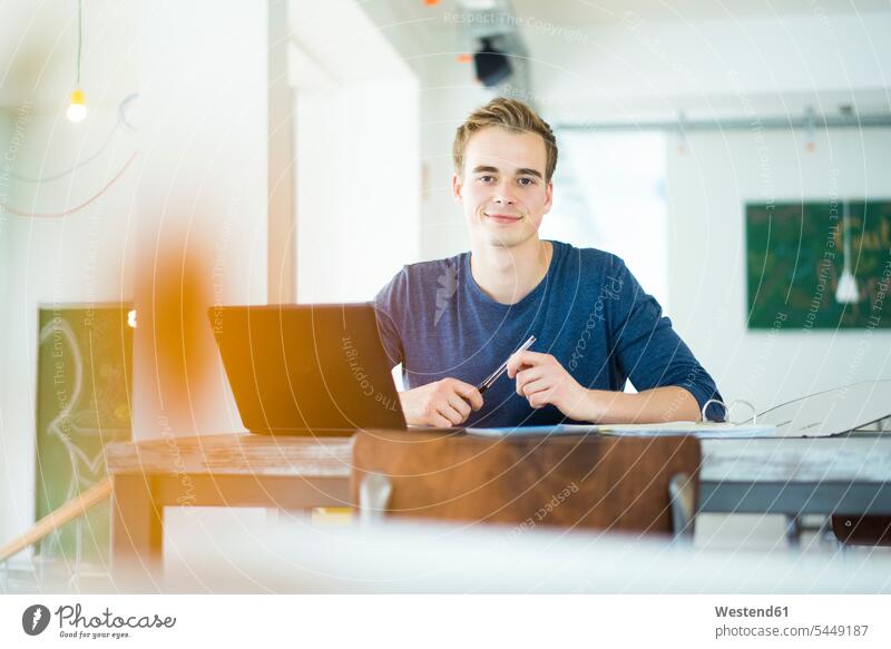 Porträt eines lächelnden Studenten, der mit einem Laptop arbeitet Portrait Porträts Portraits Hochschueler Studierender Hochschüler Notebook Laptops Notebooks