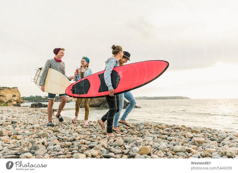 Glückliche Freunde mit Surfbrettern am steinigen Strand Surfer Wellenreiter glücklich glücklich sein glücklichsein Beach Straende Strände Beaches surfboard