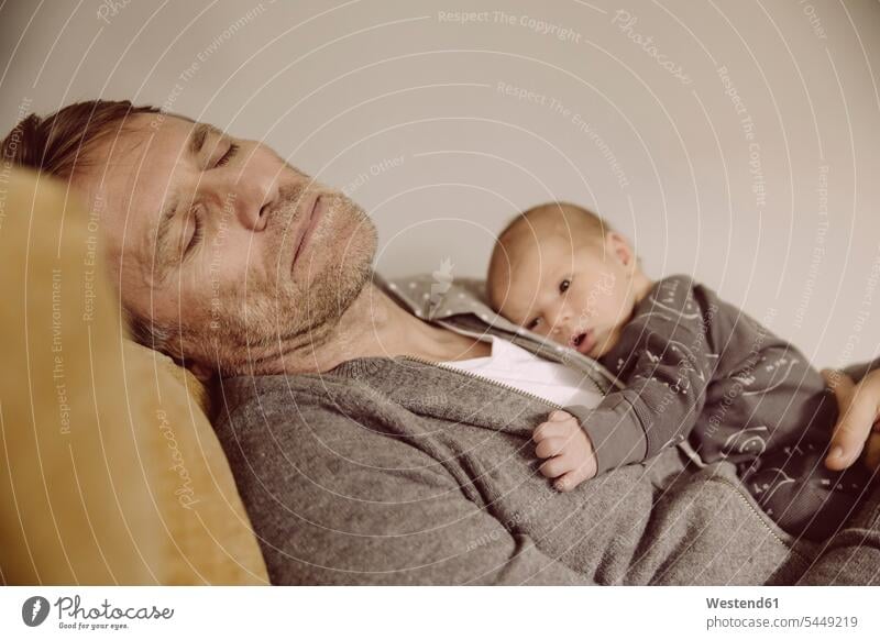 Vater macht ein Nickerchen mit wachem Neugeborenen auf der Brust schlafen schlafend Baby Babies Babys Saeugling Saeuglinge Säuglinge Kind Kinder Papas Väter