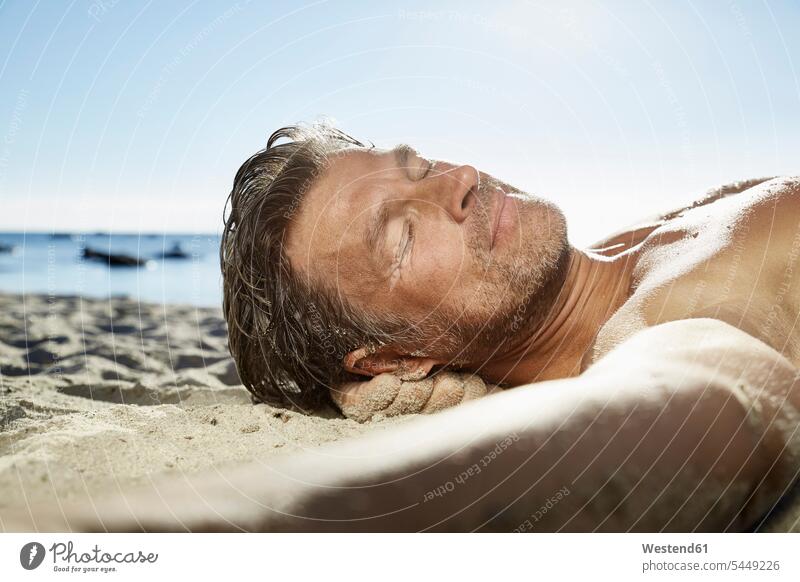 Porträt eines Mannes, der sich am Sandstrand entspannt Männer männlich Portrait Porträts Portraits Strand Beach Straende Strände Beaches Erwachsener erwachsen