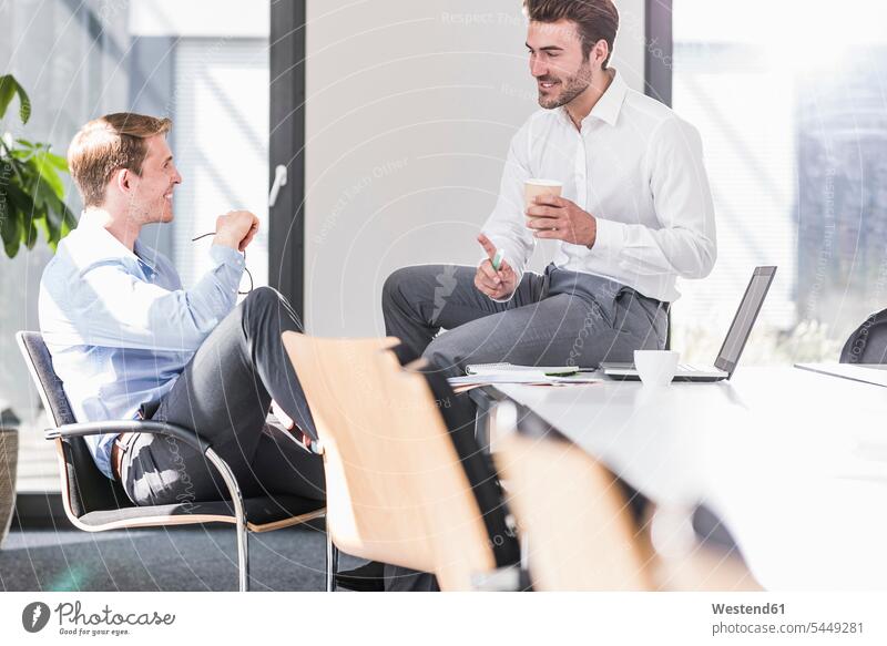 Zwei lächelnde Kollegen arbeiten gemeinsam an einem Projekt im Büro Arbeitskollegen sprechen reden Geschäftsmann Businessmann Businessmänner Geschäftsmänner