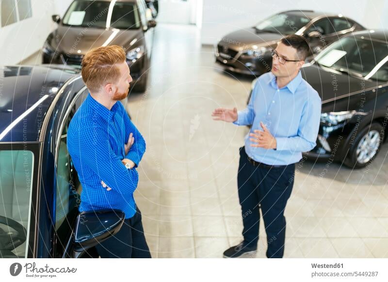 Verkäufer, der Kunden im Autohaus berät beraten beratend verkaufen aussuchen auswählen Wagen PKWs Automobil Autos Kundschaft Kauf Kraftfahrzeug Verkehrsmittel