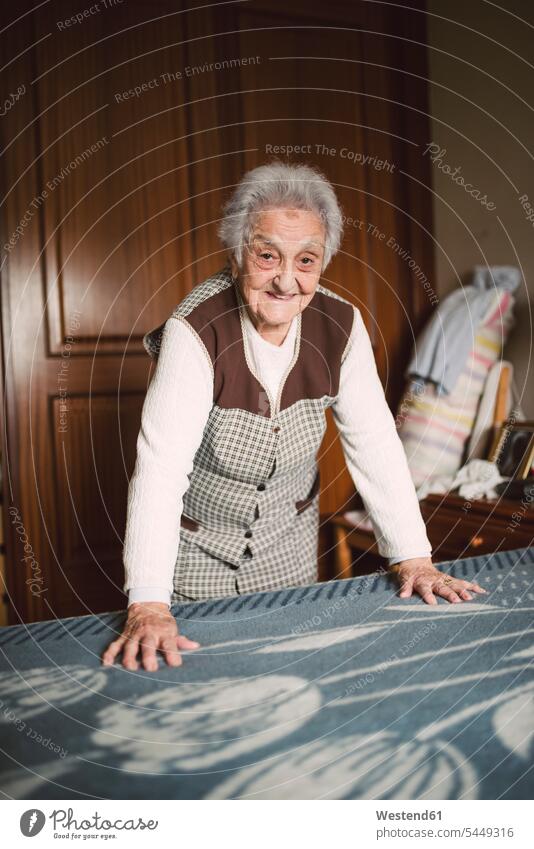 Ältere Frau legt frische Laken auf ein Bett Decke Decken Seniorin älter Seniorinnen alt das Bett machen Bett beziehen Sauber Sauberkeit rein Reinlichkeit
