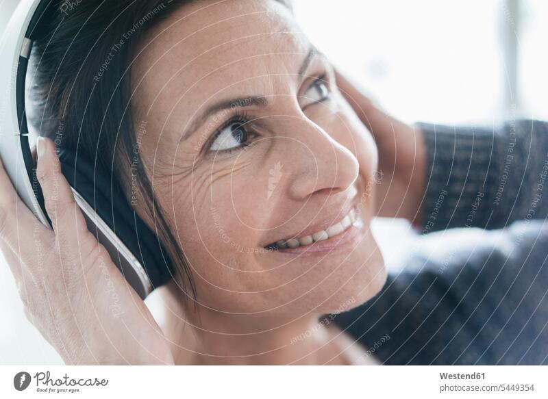 Porträt einer lächelnden Frau, die mit Kopfhörern Musik hört weiblich Frauen Portrait Porträts Portraits Kopfhoerer Erwachsener erwachsen Mensch Menschen Leute