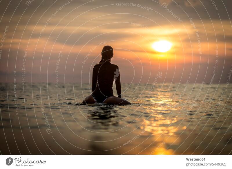 Indonesien, Bali, Surferin im Ozean bei Sonnenuntergang Meer Meere Frau weiblich Frauen Surfen Surfing Wellenreiten Gewässer Wasser Erwachsener erwachsen Mensch